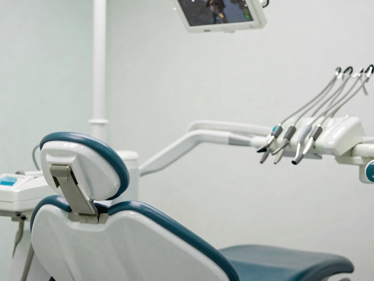 Considered close-up of a dental chair and operatory in soft even daylight, calm whites and muted blue-green tones